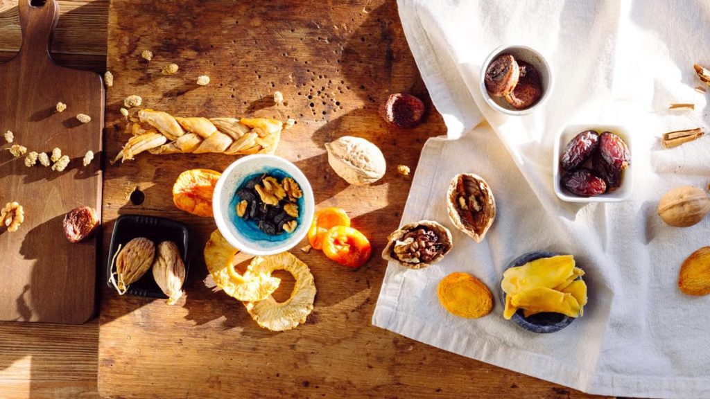 Top view of a rustic assortment of dried fruits and nuts on a wooden board, perfect for healthy snacks.